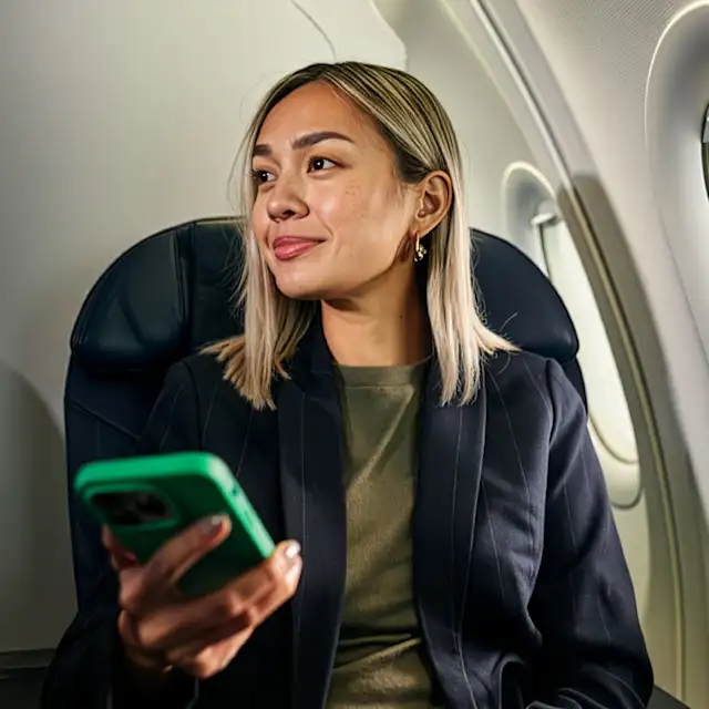 Traveler on a plane holding a phone in a green case